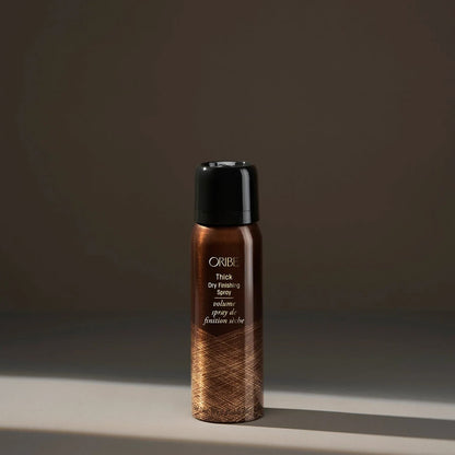 Oribe Thick Dry Finishing Spray in a bronze metallic bottle with a black cap, adds volume and thickness to hair.