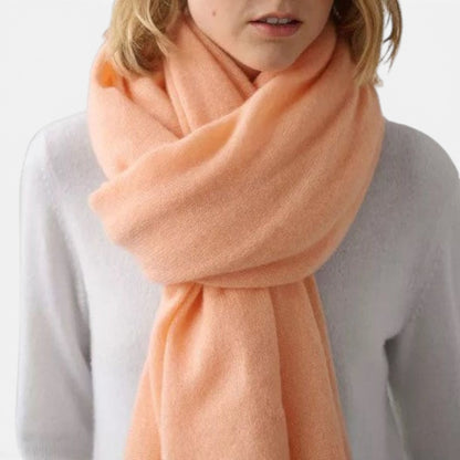 Shop Rescue Spa peach cashmere travel wrap worn as a soft, lightweight scarf over a white top.