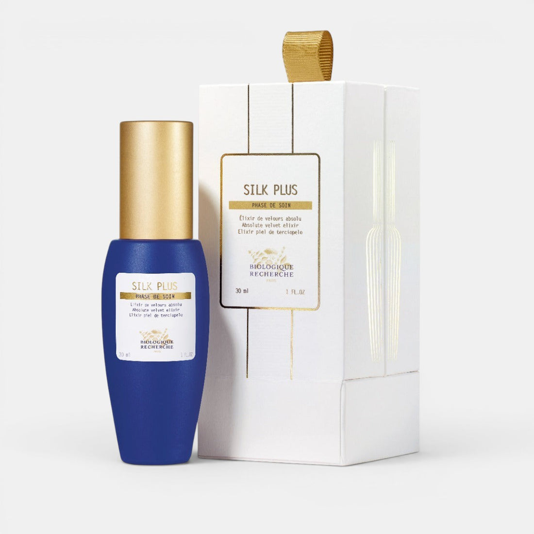 Blue Biologique Recherche Silk Plus bottle with gold cap on a white background with white branded box next to it. Mattifying &amp; Soothing Serum for Sensitive, Oily Skin.