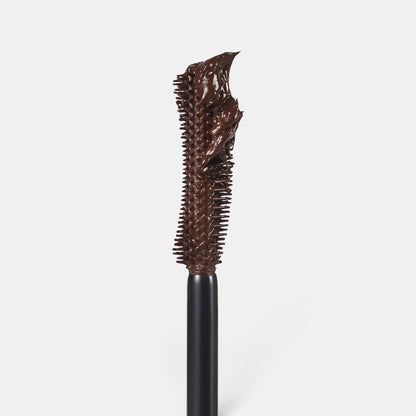 Texture photo of Revitalash length define mascara in dark brown. Tall upright applicator, light gray background.