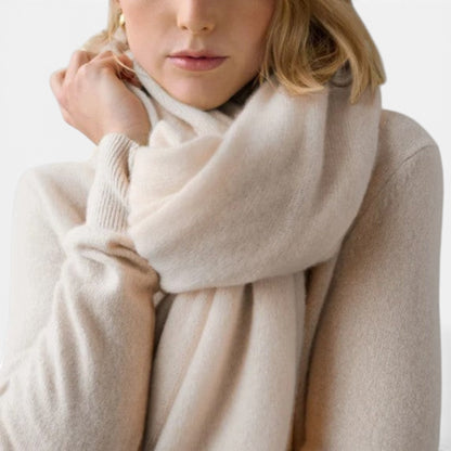 Shop Rescue Spa cashmere travel wrap in a soft cream color, worn as a cozy, lightweight scarf by a woman.