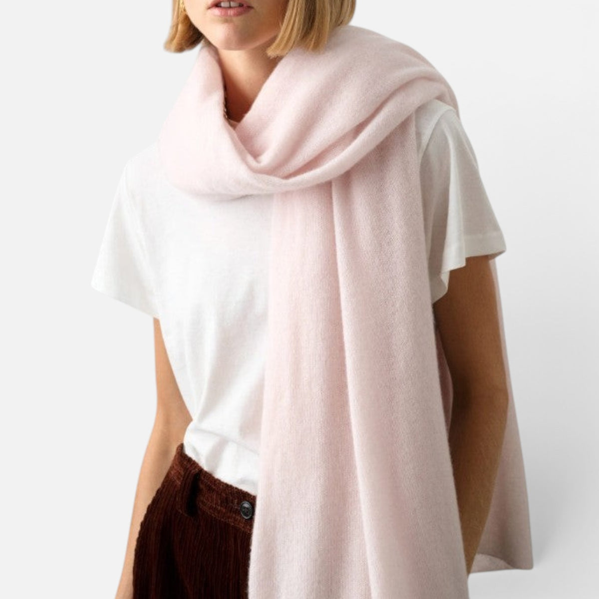 Shop Rescue Spa soft pale pink cashmere travel wrap draped over a woman wearing a white t-shirt