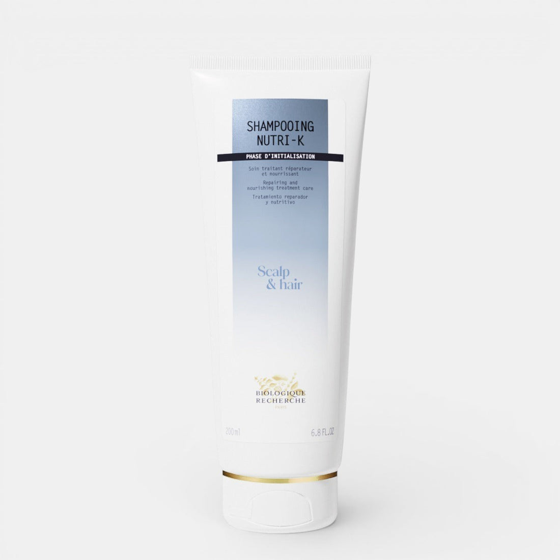 Biologique Recherche Shampooing Nutri-K in a white, squeezable tube with blue lettering and the Biologique Recherche logo, displayed on a clean white background. A nourishing shampoo designed to repair and hydrate dry, damaged hair.