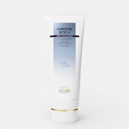 Biologique Recherche Shampooing Nutri-K in a white, squeezable tube with blue lettering and the Biologique Recherche logo, displayed on a clean white background. A nourishing shampoo designed to repair and hydrate dry, damaged hair.