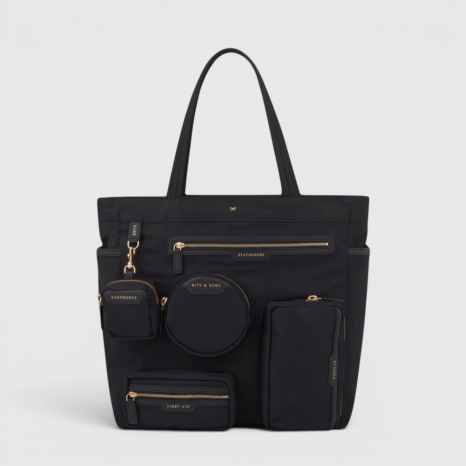 Shop Rescue Spa Anya Hindmarch black recycled nylon commuter tote with multiple external zip pockets and gold hardware
