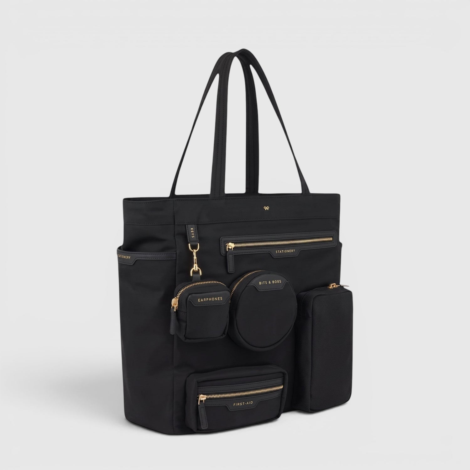 Shop Rescue Spa Anya Hindmarch black recycled nylon commuter tote with gold-tone zip pockets and external pouches.