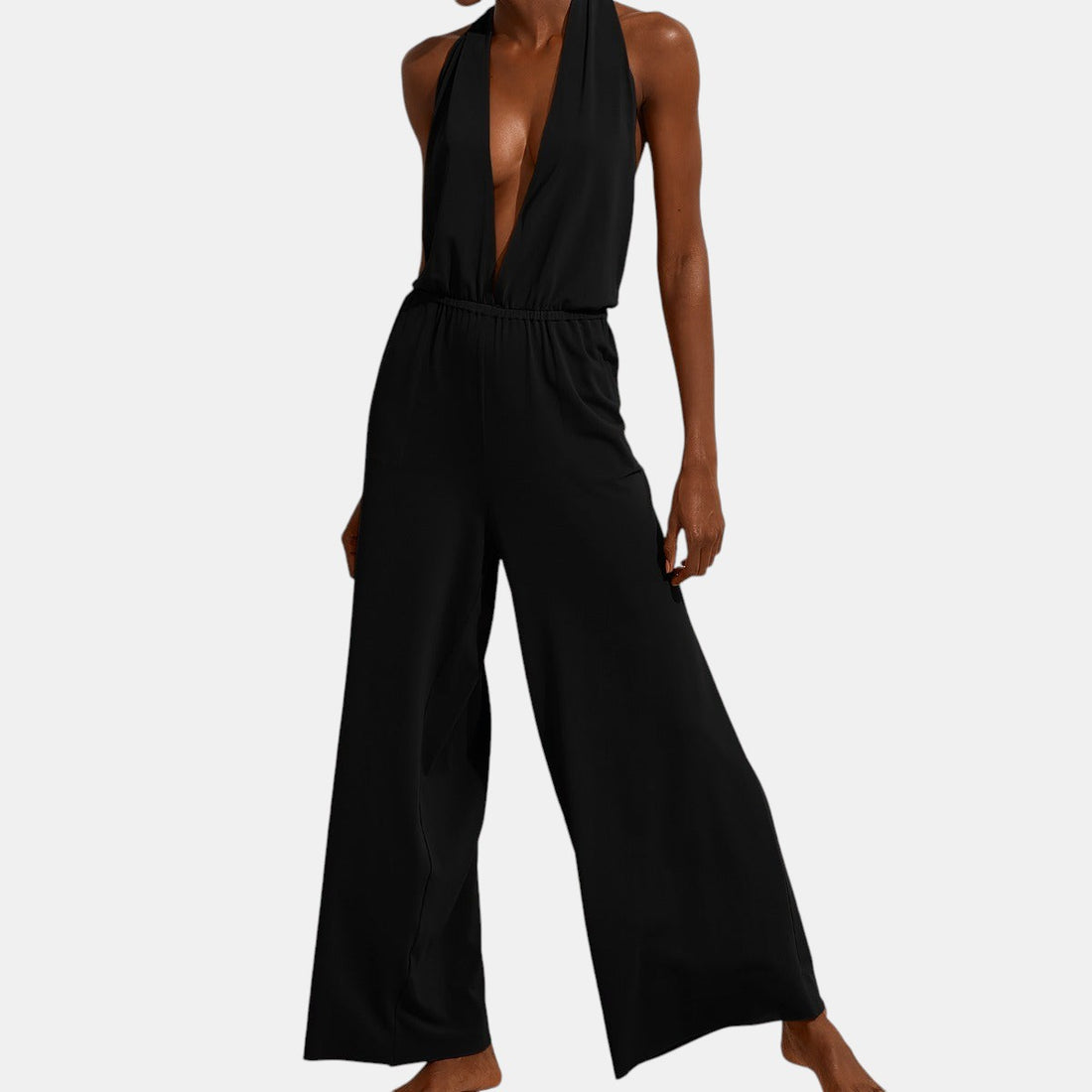 Shop Rescue Spa Arjuna black loose jumpsuit with deep V neckline, halter tie, and raw hem wide-leg trousers.