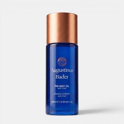 Shop Rescue Spa Augustinus Bader The Body Oil in a blue glass bottle with a metallic copper cap, 100 mL size.