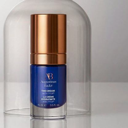 Shop Rescue Spa Augustinus Bader The Cream moisturizer in a blue bottle with a metallic gold cap under a glass dome.