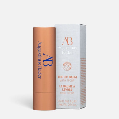 Shop Rescue Spa Augustinus Bader The Lip Balm in a copper-toned tube with its matching white product box.