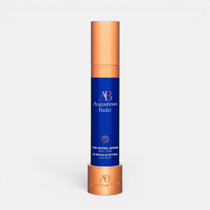 Shop Rescue Spa Augustinus Bader The Retinol Serum in a blue bottle with a metallic copper cap and matching stand.