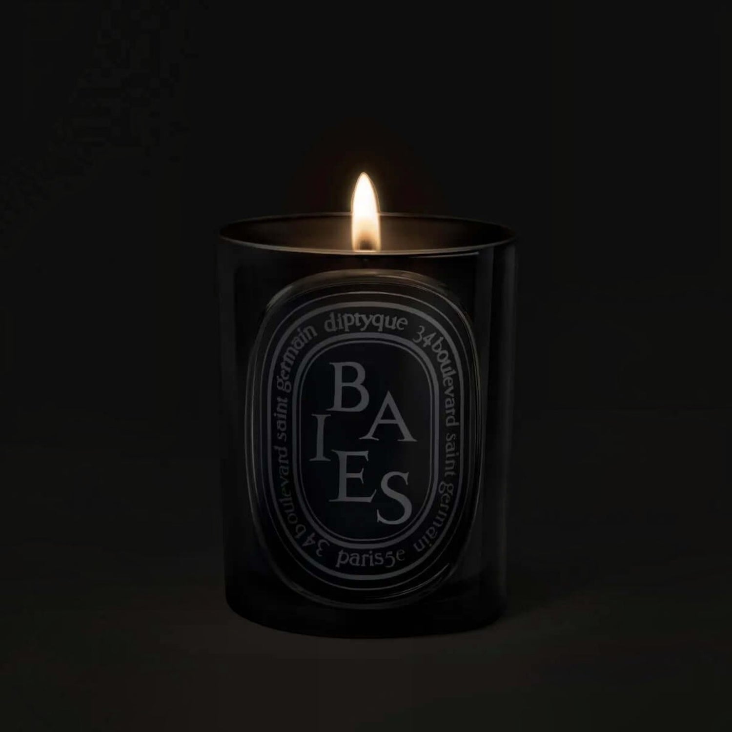 Shop Rescue Spa Baies scented candle in a black glass vessel with a glowing flame against a dark background