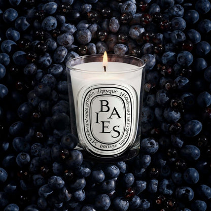 Shop Rescue Spa Baies candle in a glass vessel surrounded by a bed of fresh dark blackcurrants and blueberries