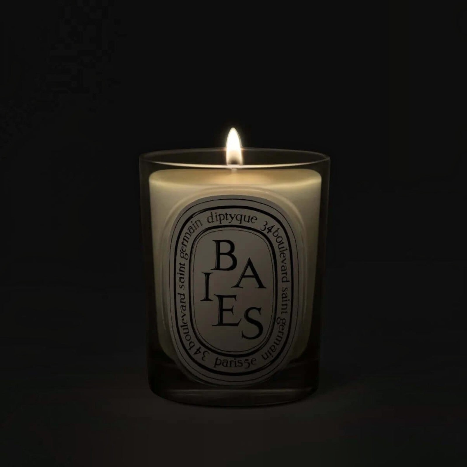 Shop Rescue Spa Baies candle in a glass vessel with a glowing flame against a dark background