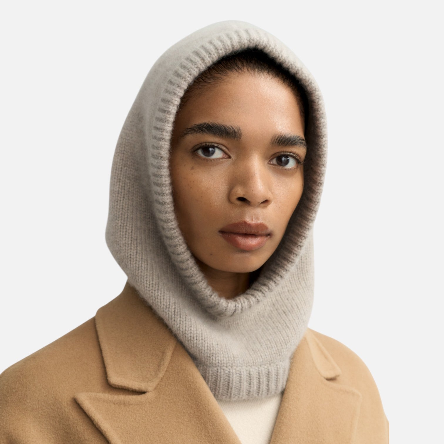 Shop Rescue Spa chunky knit beige cashmere balaclava worn by a model in a camel coat