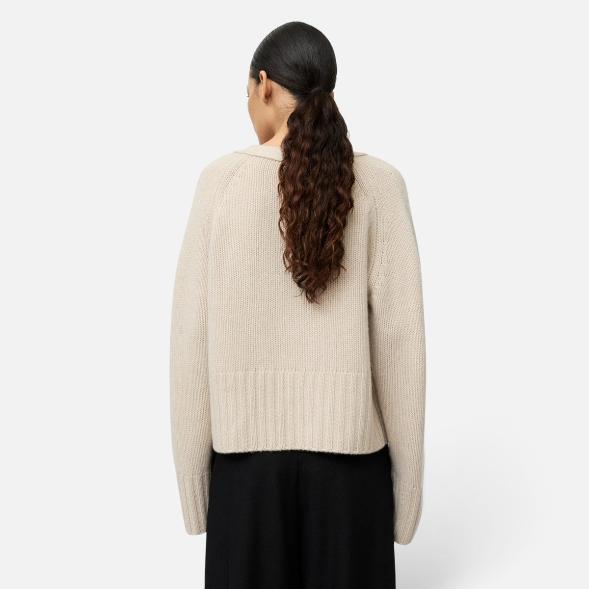 Back view of a model wearing a Shop Rescue Spa chunky knit beige 100% cashmere cardigan with a relaxed fit.