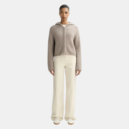 Shop Rescue Spa chunky knit cashmere hoodie in beige with a front zipper, worn by a model with cream trousers.