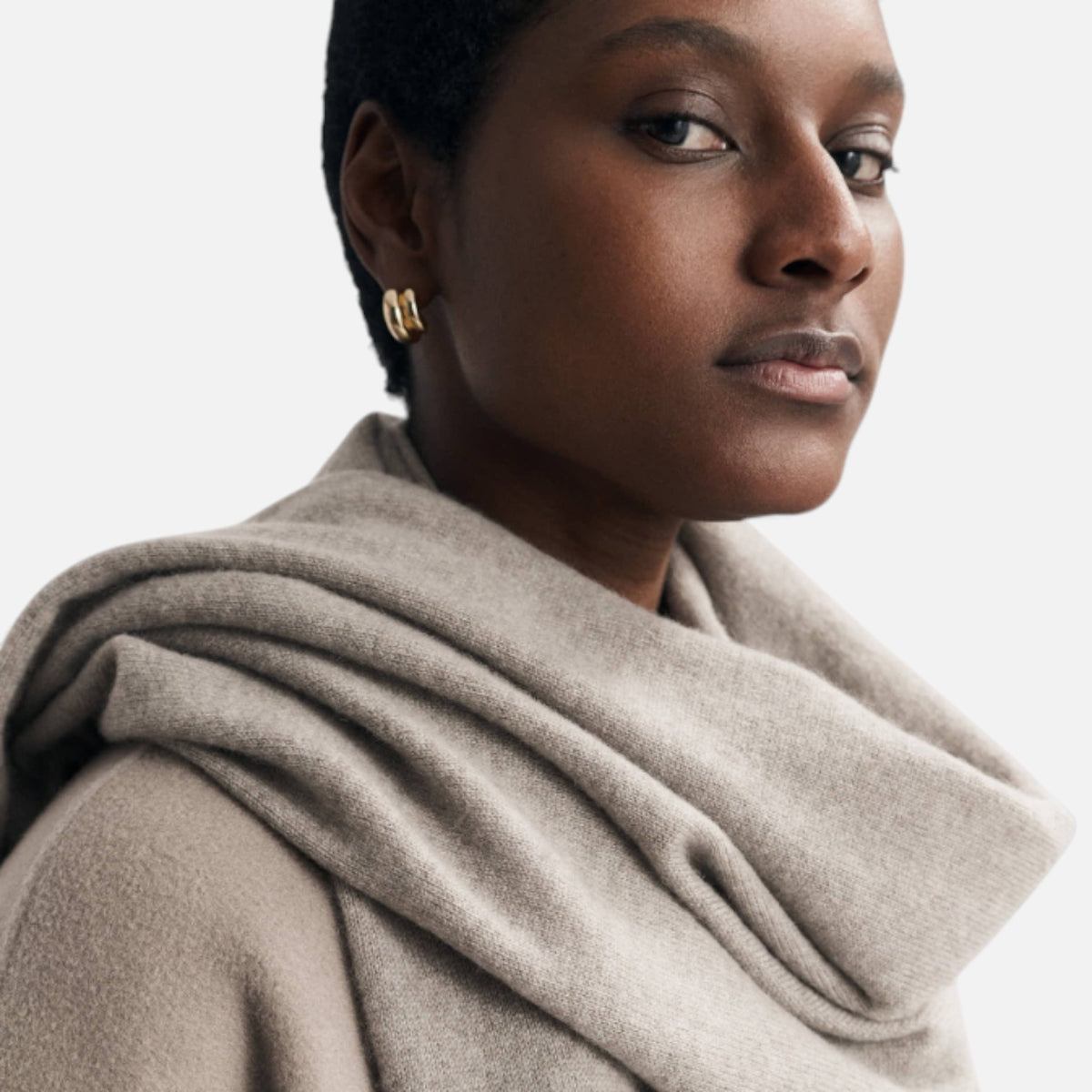 Shop Rescue Spa unisex fine knit beige cashmere scarf worn by a model with gold hoop earrings