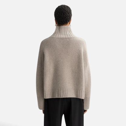 Back view of a model wearing a Shop Rescue Spa chunky beige cashmere turtleneck sweater with ribbed details.