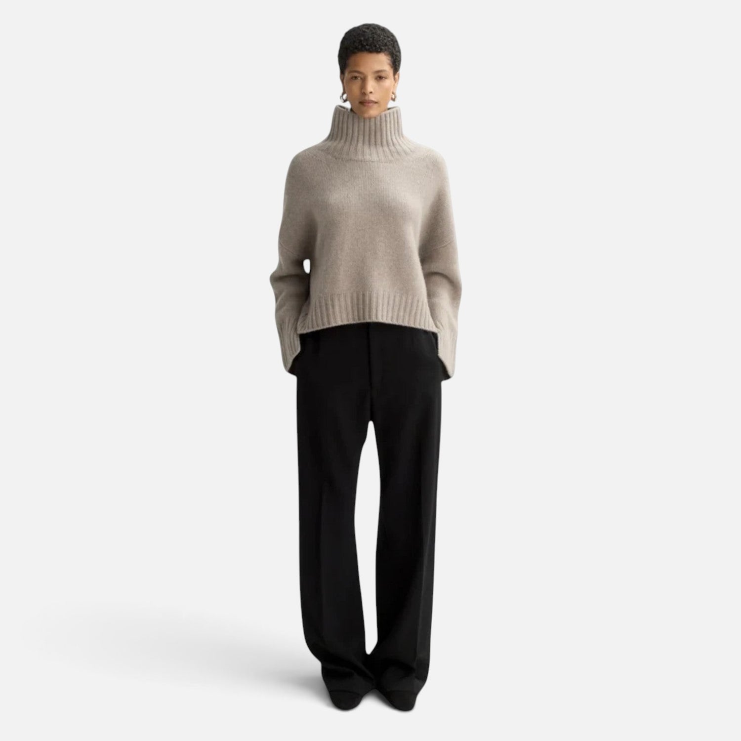 Model wearing a Shop Rescue Spa chunky beige cashmere turtleneck sweater with sleeve slits and a relaxed fit.