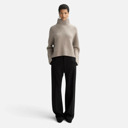 Model wearing a Shop Rescue Spa chunky beige cashmere turtleneck sweater with sleeve slits and a relaxed fit.