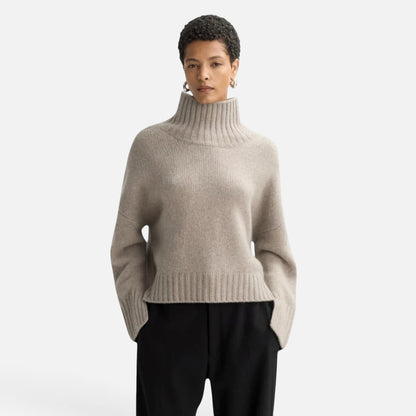 Model wearing a Shop Rescue Spa chunky beige cashmere turtleneck sweater with relaxed fit and sleeve slits.