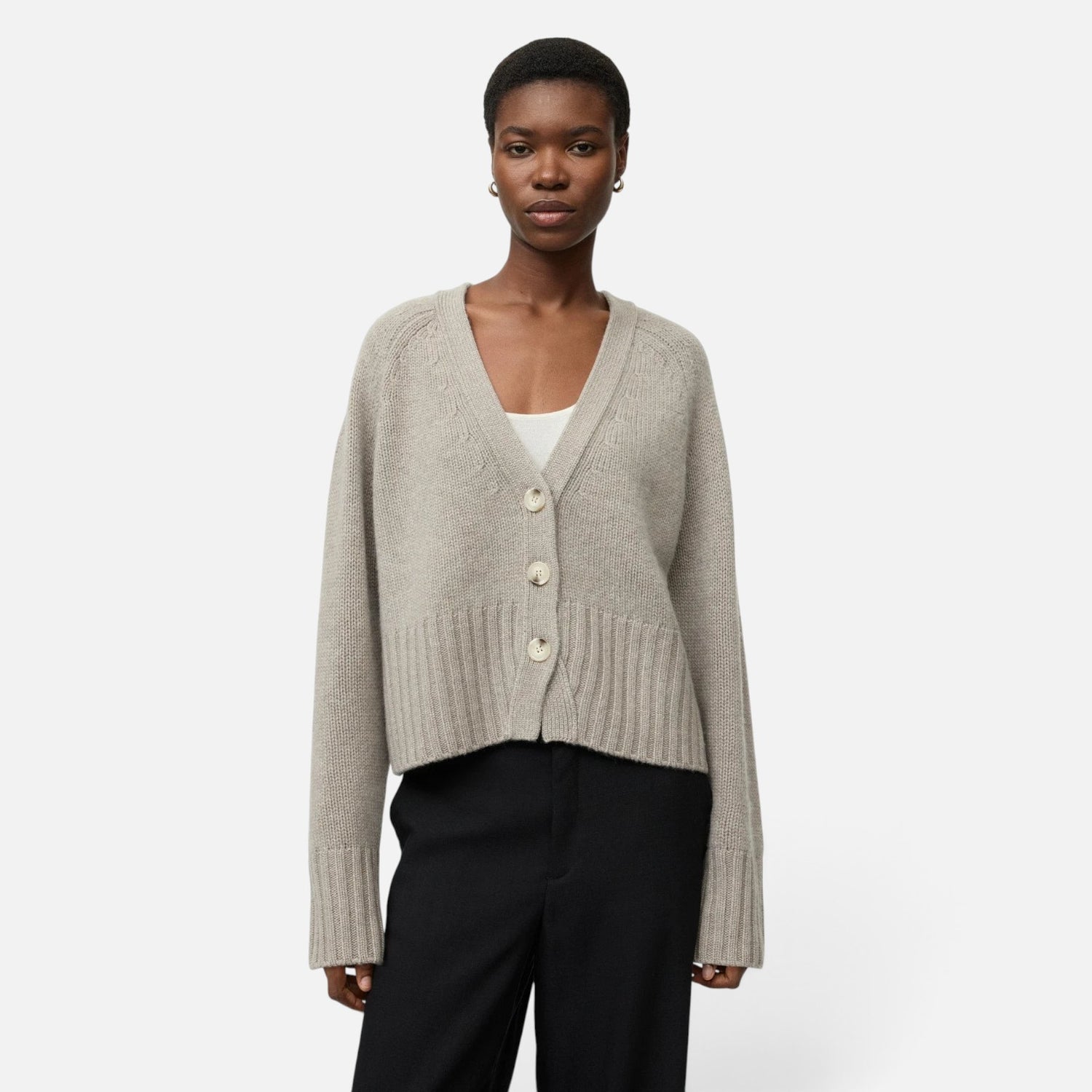 Shop Rescue Spa chunky beige cashmere V-neck cardigan with button front, worn by a model in a relaxed fit.