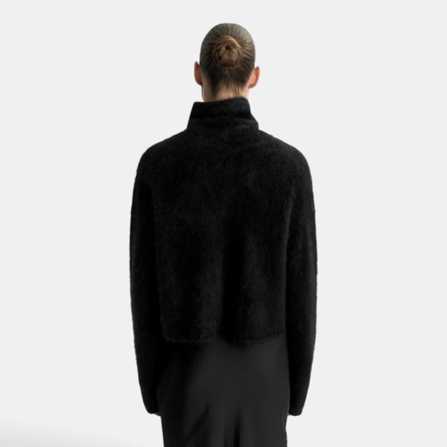 Back view of a model wearing a black Shop Rescue Spa brushed cashmere turtleneck sweater with a regular fit.