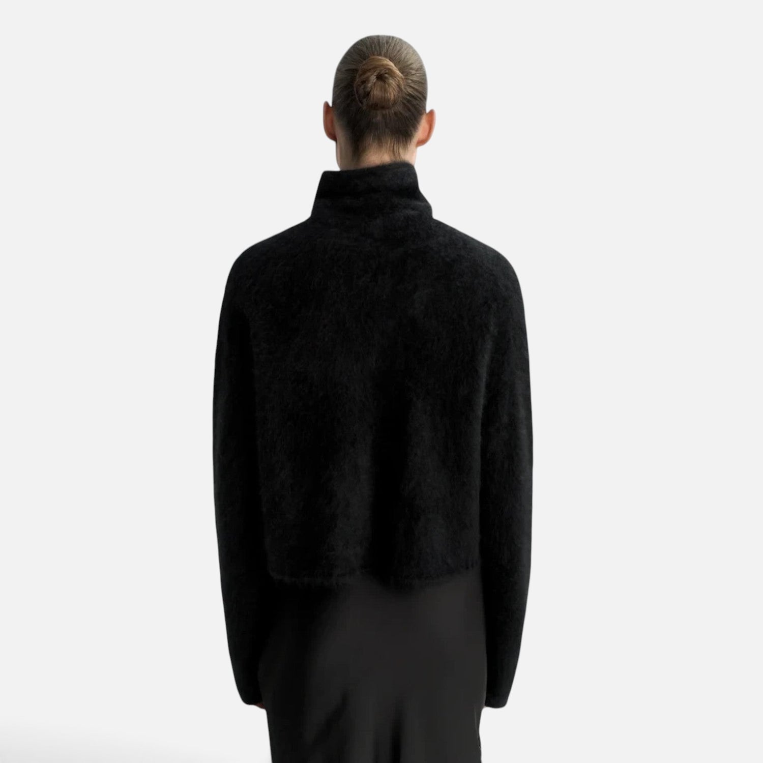 Back view of a model wearing a Shop Rescue Spa black chunky knit cashmere turtleneck sweater with a relaxed fit.