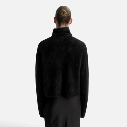 Back view of a model wearing a Shop Rescue Spa black chunky knit cashmere turtleneck sweater with a relaxed fit.