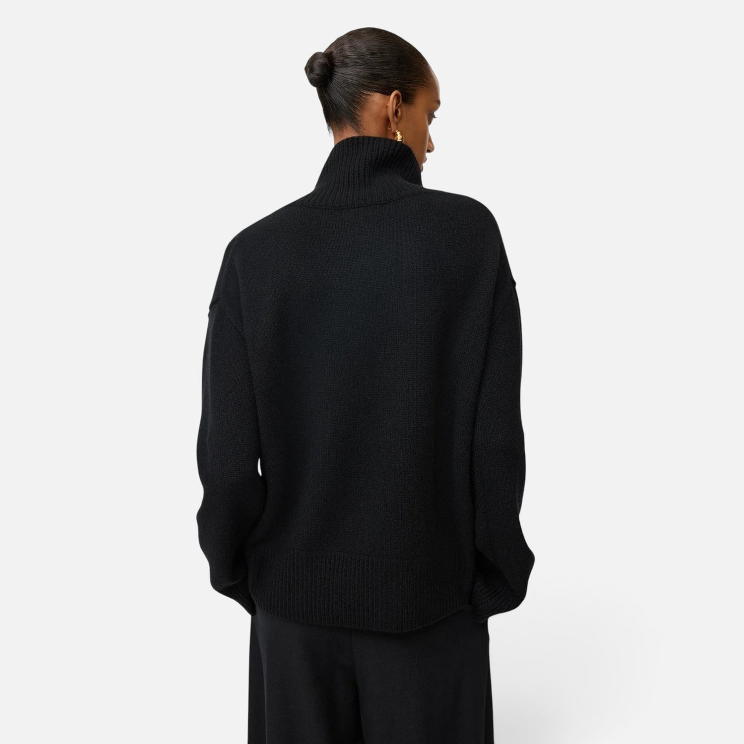 Back view of a model wearing a Shop Rescue Spa oversized black chunky knit cashmere turtleneck sweater.