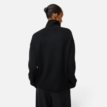 Back view of a model wearing a Shop Rescue Spa oversized black chunky knit cashmere turtleneck sweater.