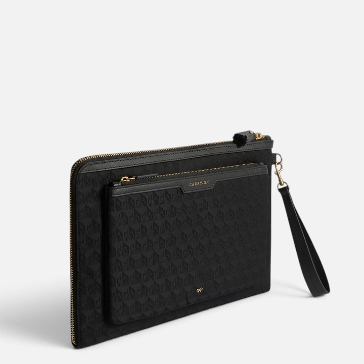 Shop Rescue Spa black nylon Logo Journey Essentials pochette with gold zip, wrist strap, and labelled exterior pockets.