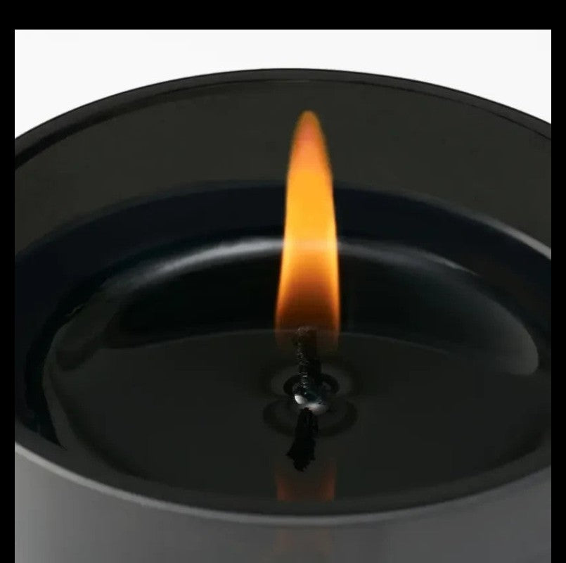 Shop Rescue Spa Bohemia candle in a black reusable glass jar with a lit flame. Woody scent with notes of vanilla and sandalwood.