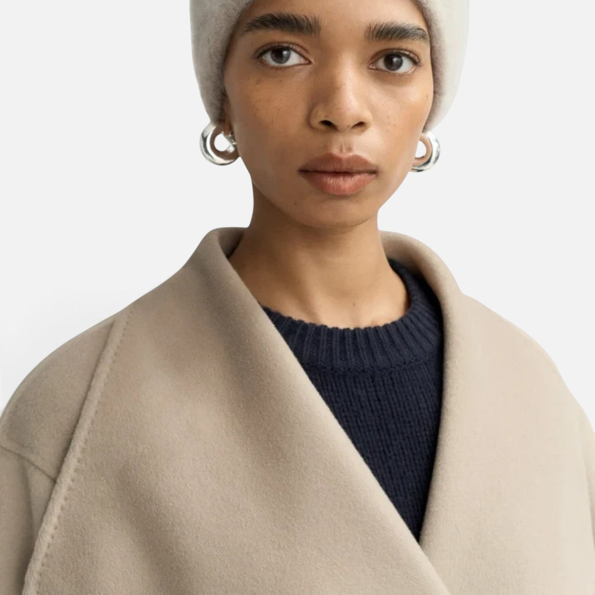 Shop Rescue Spa brushed cashmere beanie in light beige worn by a model with silver hoop earrings