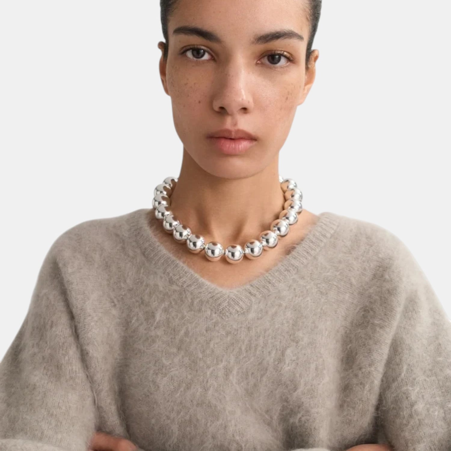 Shop Rescue Spa brushed beige cashmere v-neck sweater worn by a model with a chunky silver ball necklace