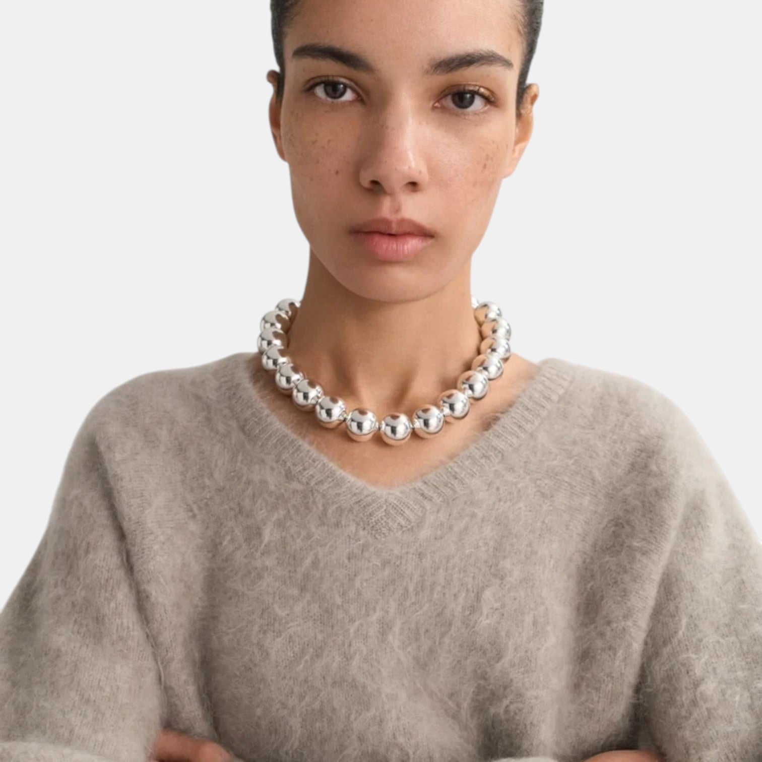 Shop Rescue Spa brushed beige cashmere v-neck sweater worn by a model with a chunky silver ball necklace