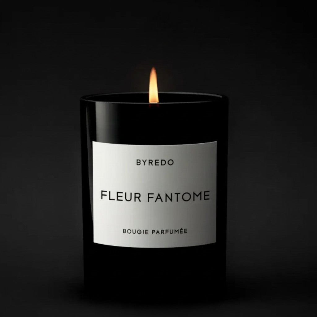 Shop Rescue Spa BYREDO Fleur Fantome scented candle in a black glass jar with a white label, lit flame.