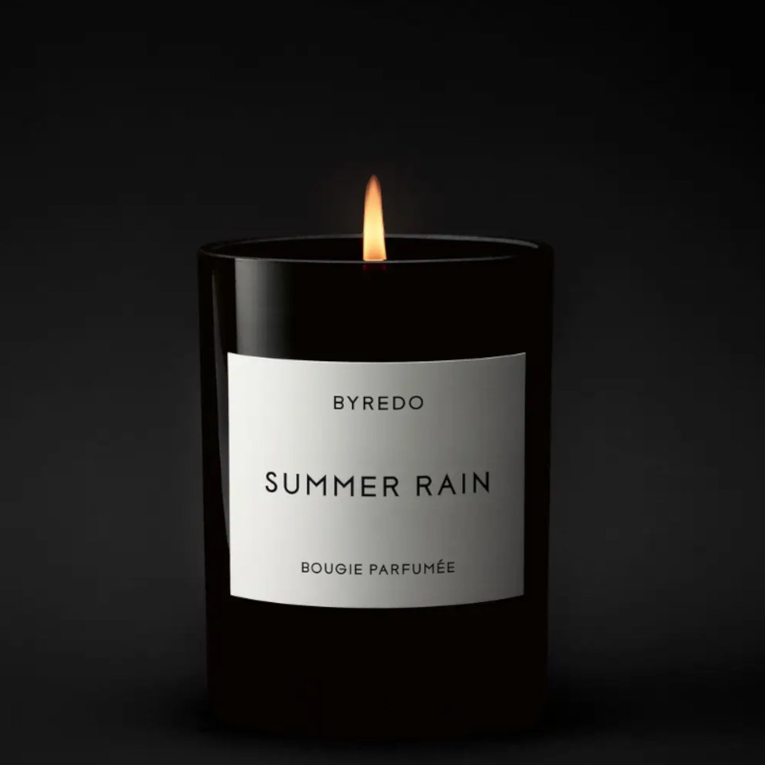 Shop Rescue Spa Byredo Summer Rain scented candle in a black glass jar with a white label. Lit flame.