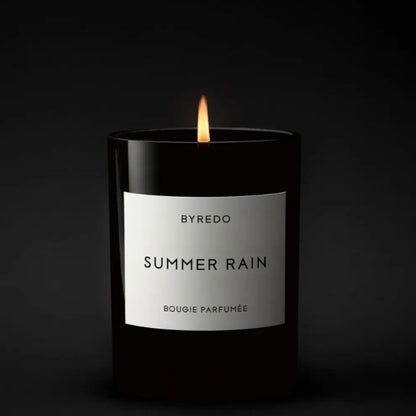 Shop Rescue Spa Byredo Summer Rain scented candle in a black glass jar with a white label. Lit flame.