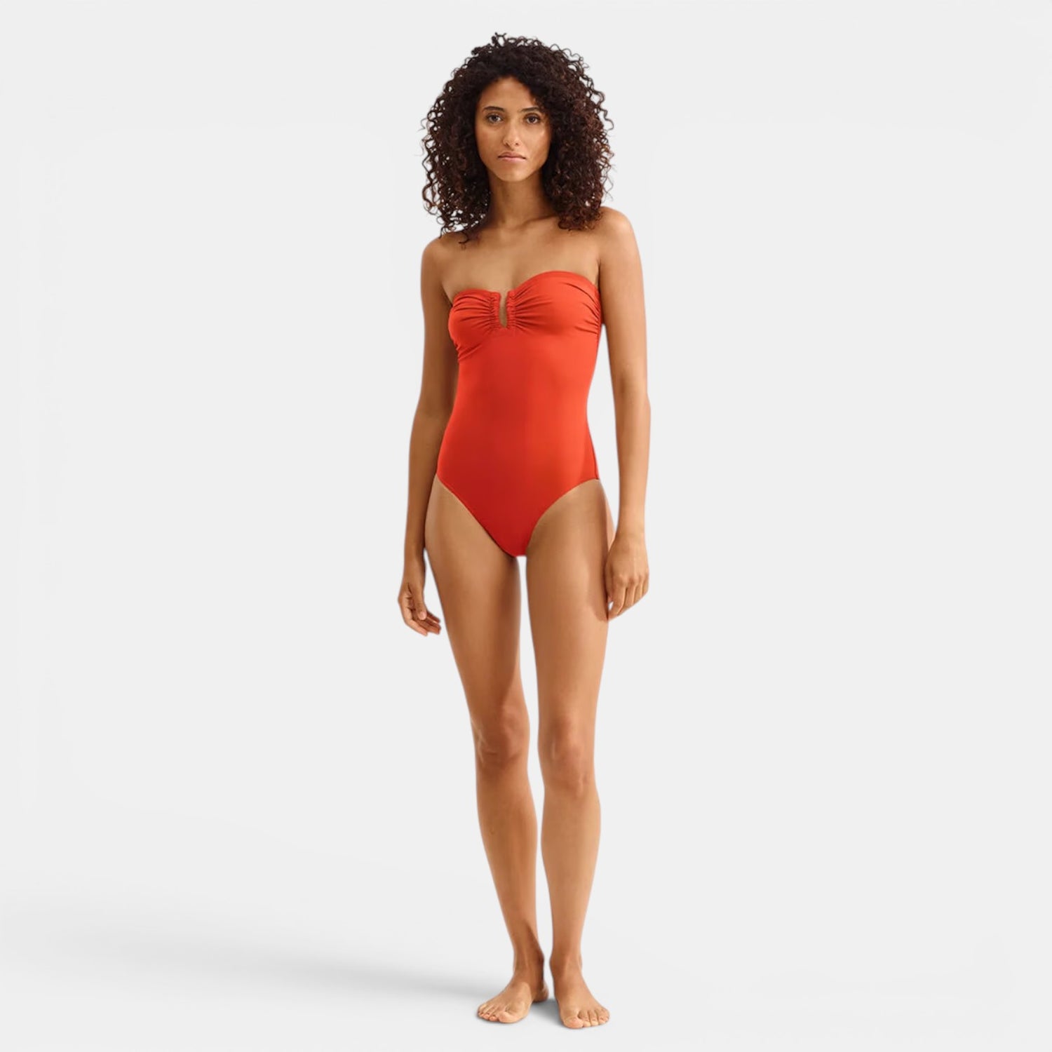 Model wearing Shop Rescue Spa Cassiopee Rooibos red one-piece bustier swimsuit with front shirring and U-shaped link.