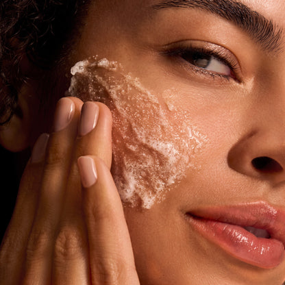 Shop Rescue Spa model applying IS Clinical Cleansing Complex Polish, a textured exfoliating scrub on her cheek.