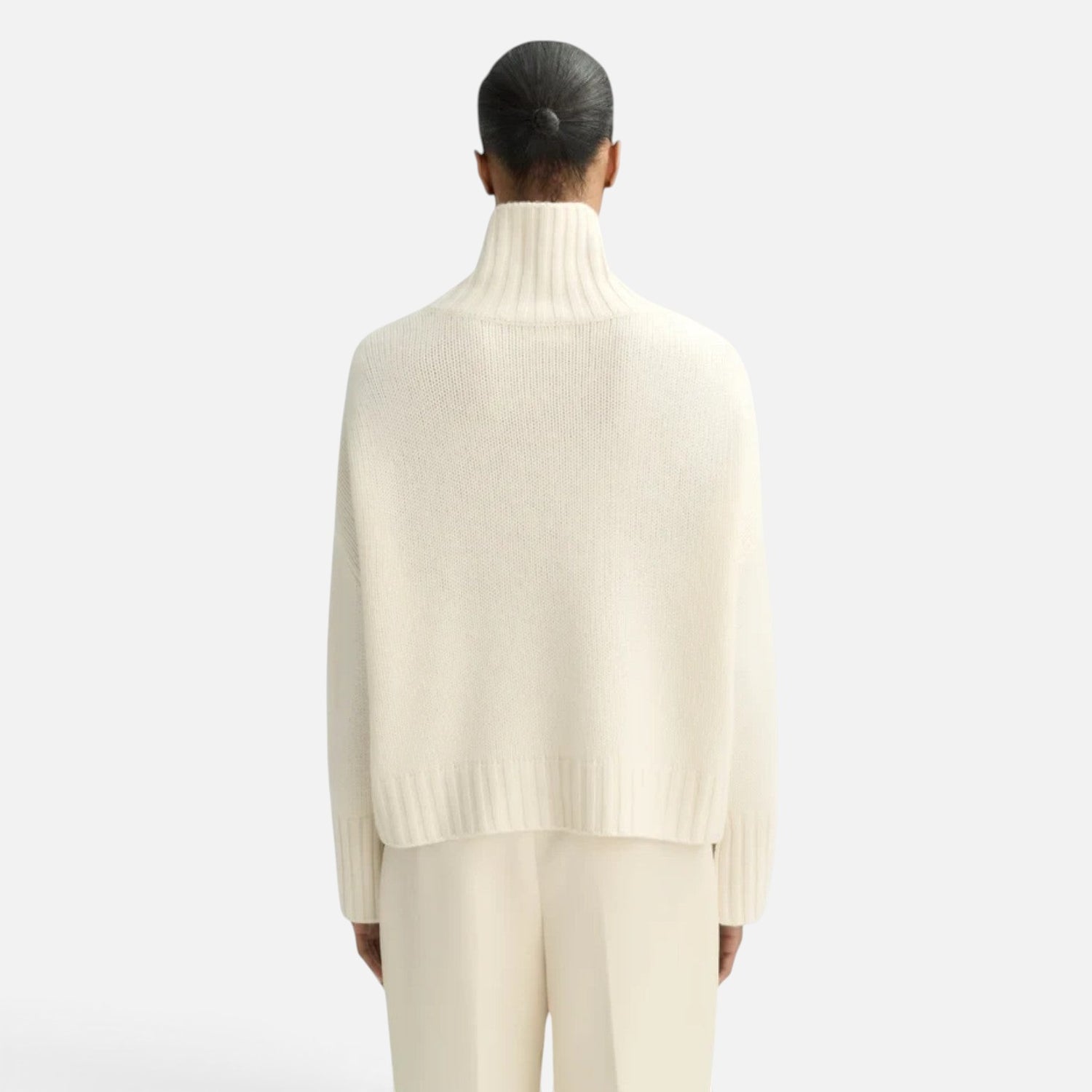 Back view of a model wearing a Shop Rescue Spa chunky cream cashmere turtleneck sweater with a relaxed fit.