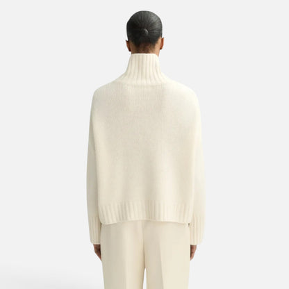 Back view of a model wearing a Shop Rescue Spa chunky cream cashmere turtleneck sweater with a relaxed fit.