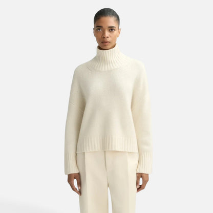 Model wearing a Shop Rescue Spa chunky cream cashmere turtleneck sweater with sleeve slits and a relaxed fit.