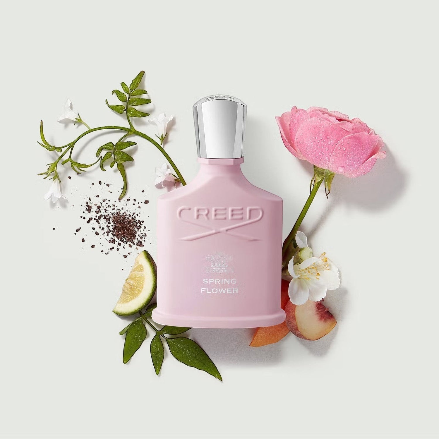 Shop Rescue Spa Creed Spring Flower 75ml perfume bottle surrounded by fresh pink roses, peach slices, and white flowers