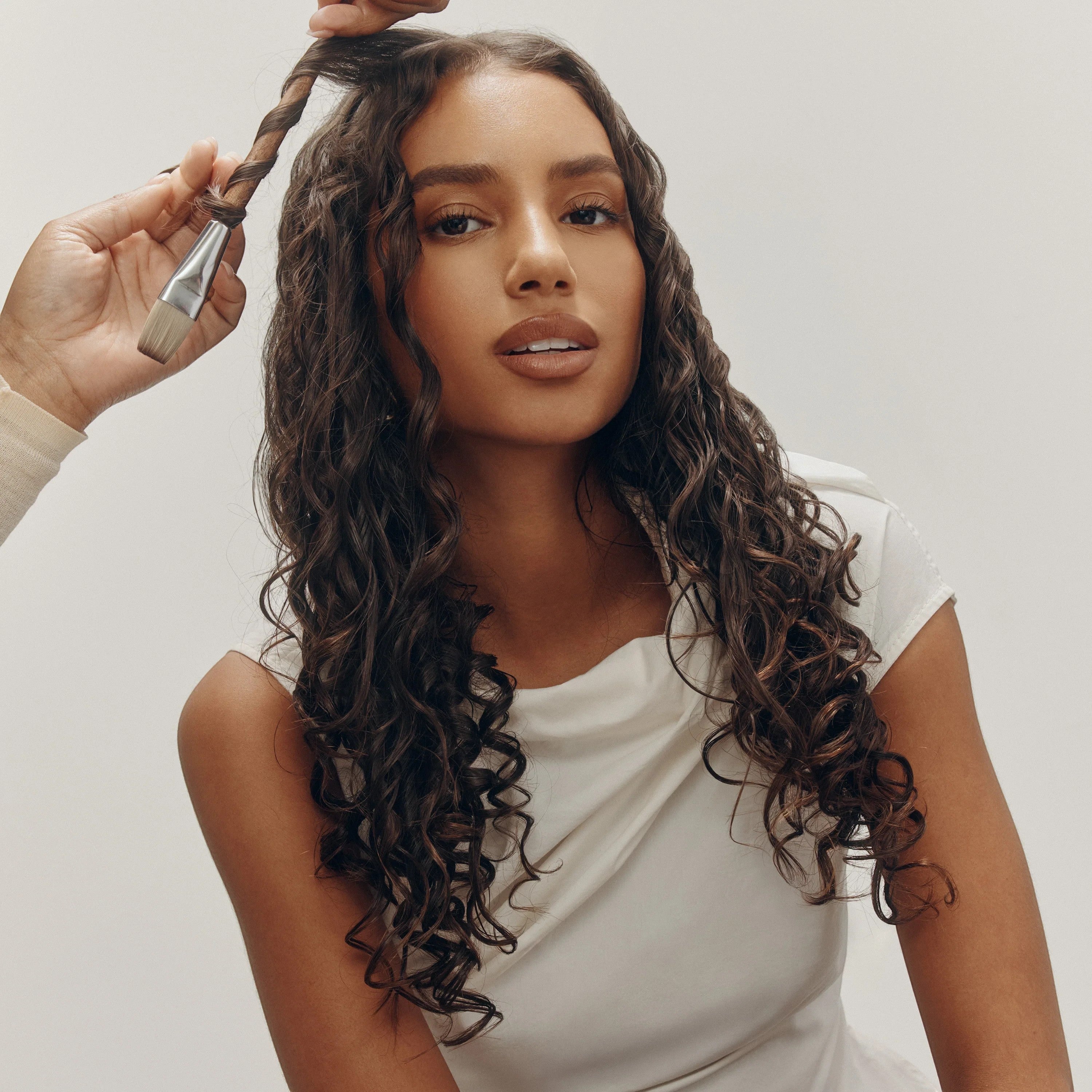 Shop Rescue Spa model with long, dark, curly hair styled with a brush and product for definition and shine.