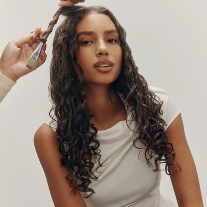 Shop Rescue Spa model with long, dark, curly hair styled with a brush and product for definition and shine.