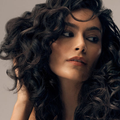 Shop Rescue Spa Curl Shaping Mousse on dark, wavy hair, adding definition and shine.