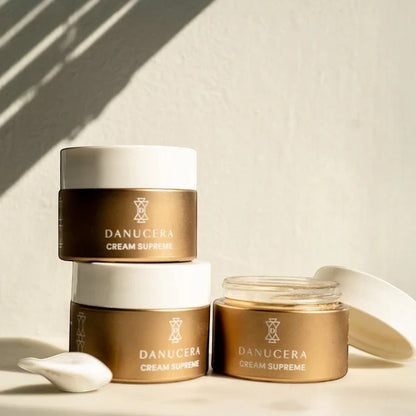 Shop Rescue Spa Danucera Cream Supreme moisturizer jars in gold and white packaging on a sunny surface.